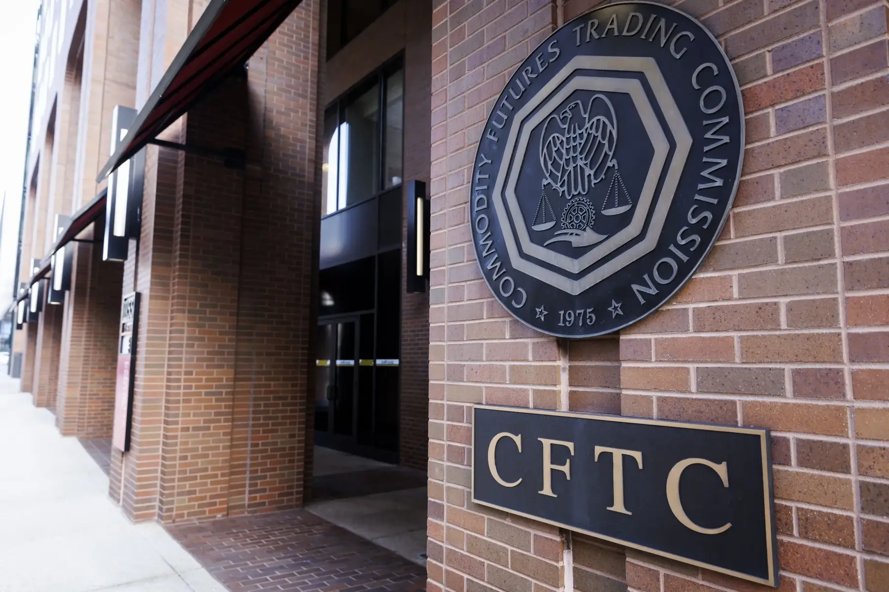 Exterior brick wall of the CFTC building featuring the official seal and a plaque reading CFTC