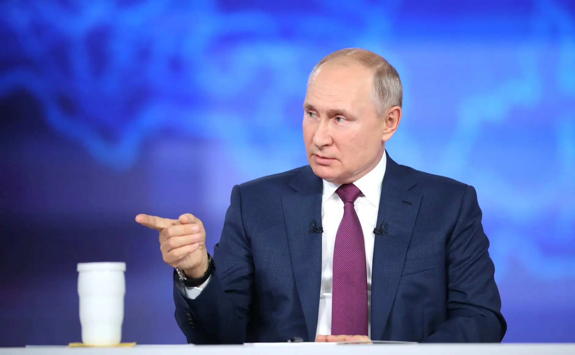 Wladimir Putin in einem dunkelblauen Anzug und einer weinroten Krawatte während einer Rede