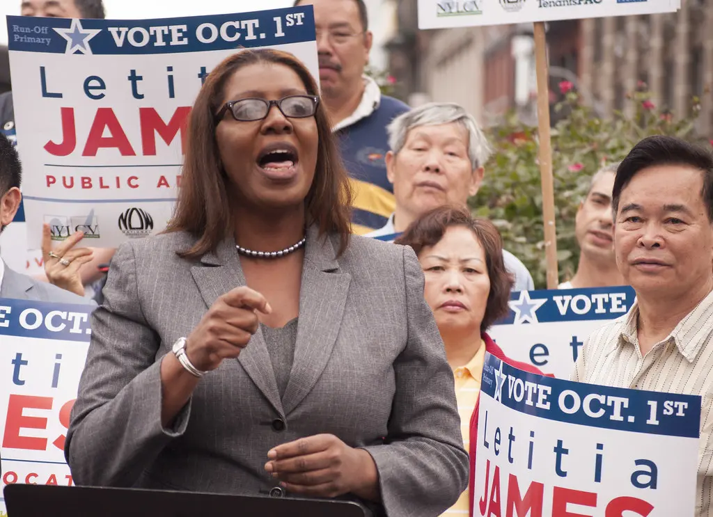 Letitia James spreekt tijdens een campagne-evenement met campagneborden op de achtergrond.