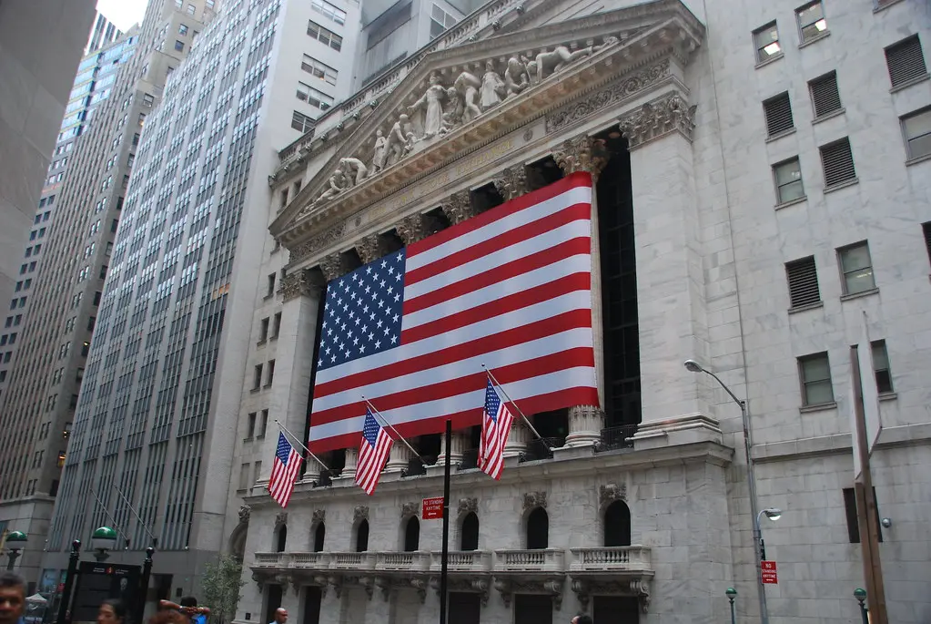De voorgevel van het gebouw van de New York Stock Exchange met een grote Amerikaanse vlag.