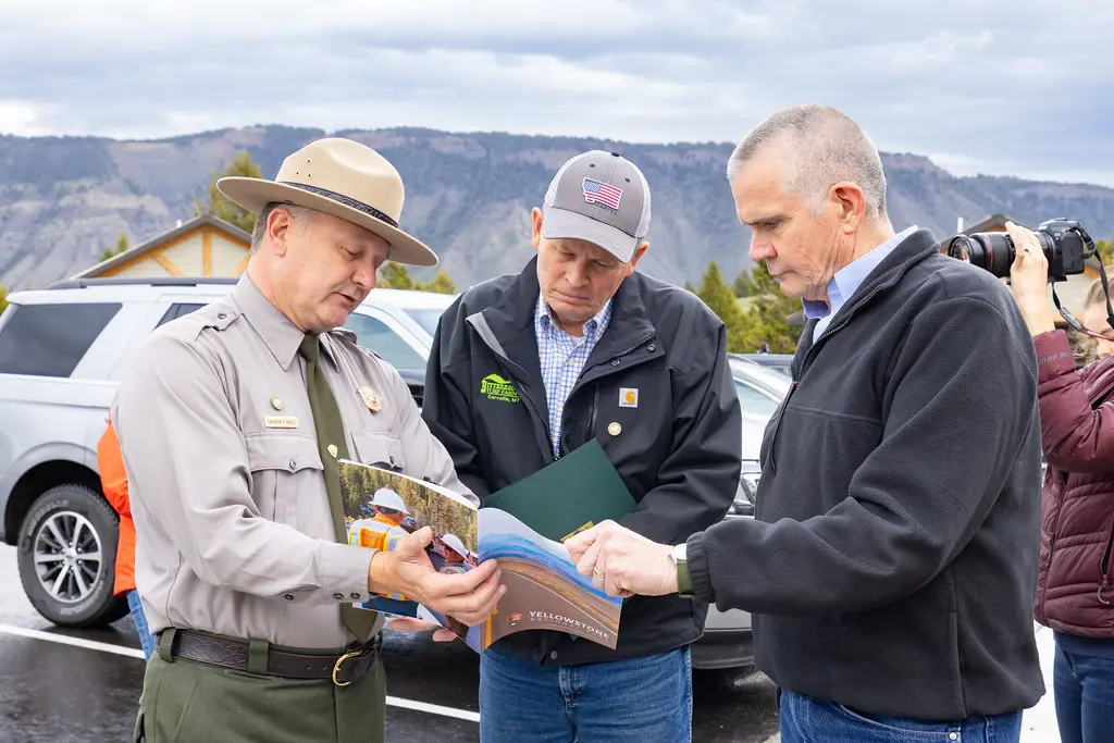 Steve Daines kijkt samen met andere mannen naar een brochure over Yellowstone.
