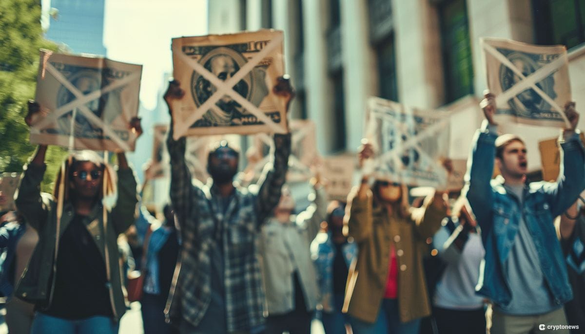 A crowd of protestors hold signs with a dollar bill crossed out, demonstrating against the proposed FTX payout plan.