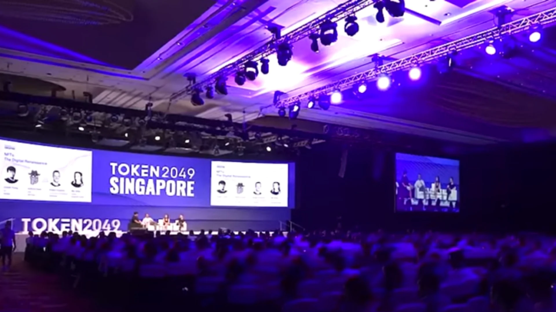 An audience seated in a large hall at the TOKEN2049 Singapore event with a large screen displaying the event name.
