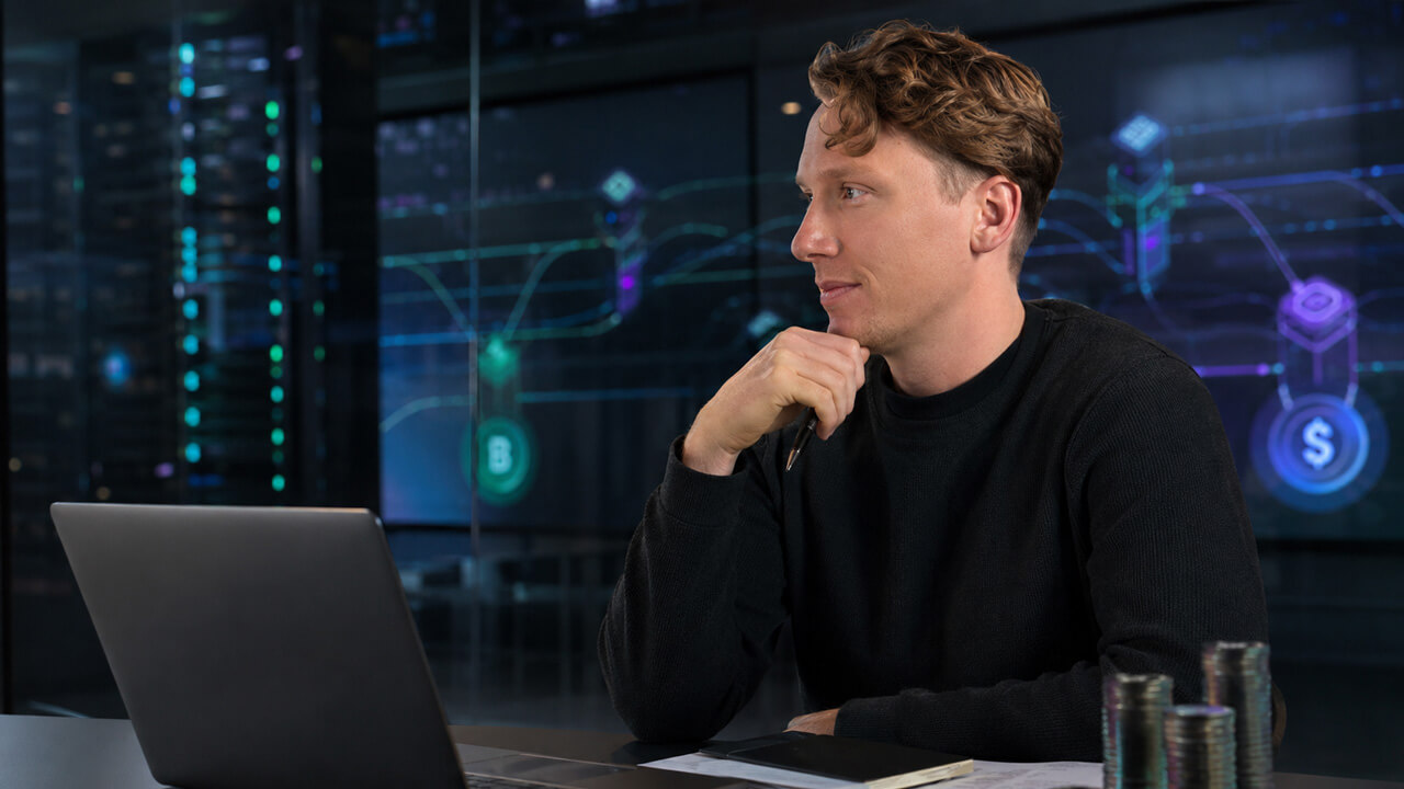 Technology entrepreneur seated at a laptop with blockchain network visualizations in the background, representing digital asset innovation, fintech development, and crypto infrastructure planning.